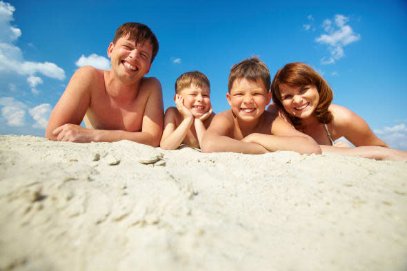 Photo of happy family sunbathing on the beach