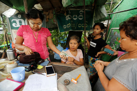 Zin Mar (L), the owner of Thiha Hair Purchasing and Sales, cuts and buys woman's hair at Insein hair market in Yangon, Myanmar June 18, 2018. Picture taken June 18, 2018. REUTERS/Ann Wang