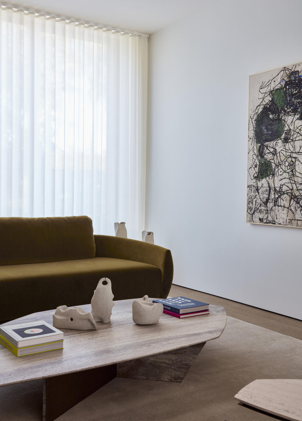 green velvet sofa in living room with large stone coffee table with angular edges