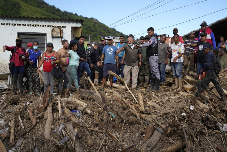 Lawmaker Diosdado Cabello, center right with face mask, tells Venezuela's President Nicolas Maduro where to walk during a visit the area flooded in Las Tejerias, Venezuela, Monday, Oct. 10, 2022. A fatal landslide fueled by flooding and days of torrential rain swept through this town in central Venezuela. (AP Photo/Matias Delacroix)