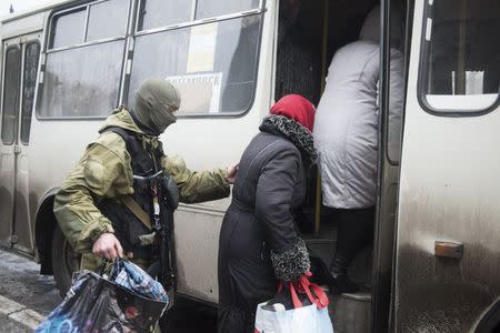 A member of the Ukrainian armed forces assists local residents onto a bus, to flee the military conflict, in Debaltseve, February 3, 2015. REUTERS/Sergey Polezhaka
