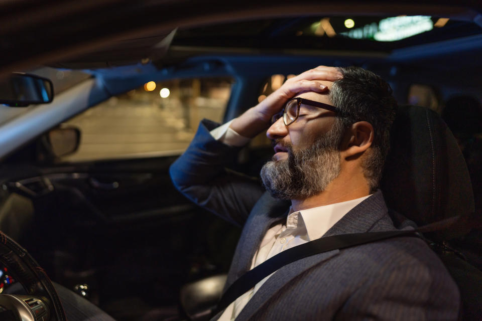 Overworked mid-adult Caucasian businessman, resting in the car on the parking lot, after long work day