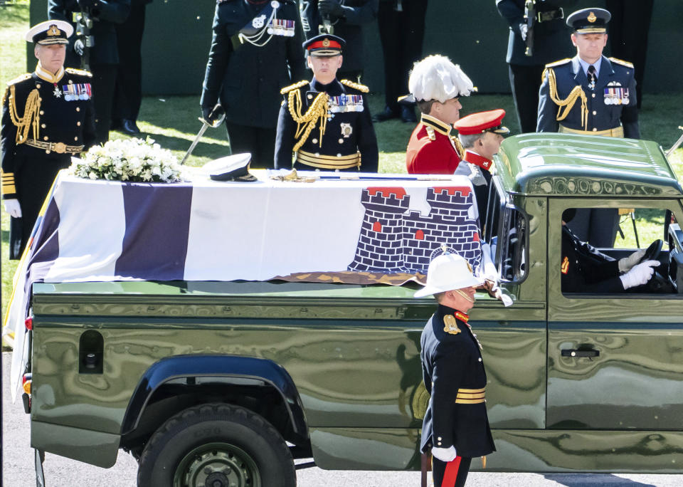 The Duke of Edinburgh's coffin, covered with his Personal Standard, is carried on the purpose built Land Rover Defender ahead of his funeral, at St George's Chapel, Windsor Castle, in Windsor, England, Saturday April 17, 2021. Prince Philip died April 9 at the age of 99 after 73 years of marriage to Britain's Queen Elizabeth II. (Danny Lawson/Pool via AP)