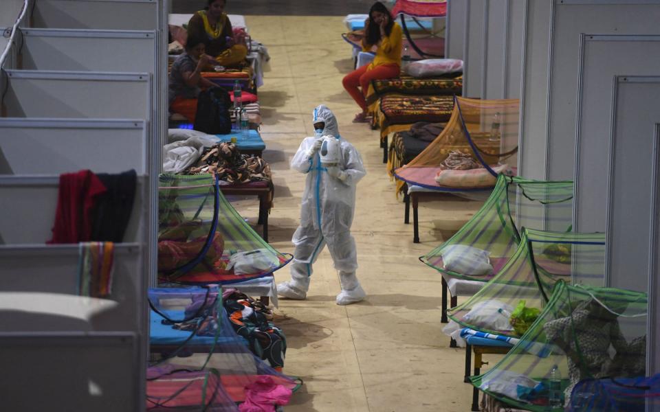 A health worker wearing a personal protective equipment (PPE) suit attends Covid-19 coronavirus patients inside a centre of the Commonwealth Games (CWG) village temporarily converted into a Covid care facility, in New Delhi - TAUSEEF MUSTAFA /AFP 