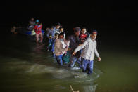 In this March 24, 2021 photo, migrant families, mostly from Central American countries, wade through shallow waters after being delivered by smugglers on small inflatable rafts on U.S. soil in Roma, Texas. The Biden administration said Monday that four families that were separated at the Mexico border during Donald Trump's presidency will be reunited in the United States this week in what Homeland Security Secretary Alejandro Mayorkas calls “just the beginning” of a broader effort. (AP Photo/Dario Lopez-Mills)