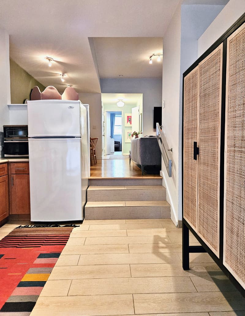 White kitchen with colorful geometric pattern runner and large rattan storage cabinets