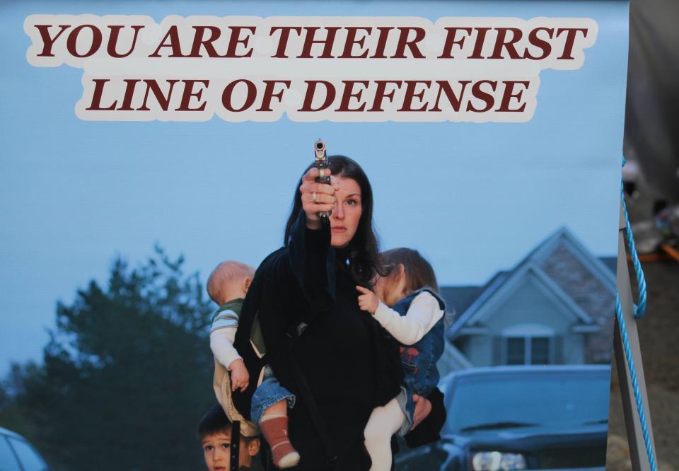 A poster at the Rod of Iron Freedom Festival depicts a woman defending young children with a hand gun.