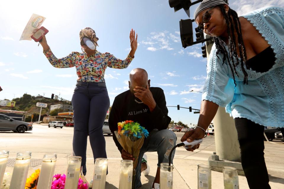 People light candles at a makeshift memorial across the street from where a fiery multi-car crash left five dead.