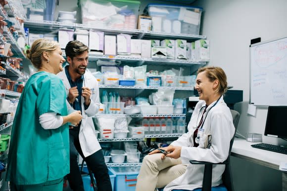 Three healthcare providers laughing while taking a break in the storeroom.