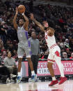 Sacramento Kings' De'Aaron Fox (5) shoots as Chicago Bulls' Coby White defends and Kings coach Mike Brown watches during the first half of an NBA basketball game Wednesday, March 15, 2023, in Chicago. (AP Photo/Charles Rex Arbogast)