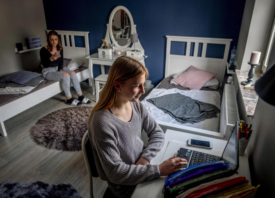 13-year-old daughter Anni, right, and her sister Leni spend time in their room in their house in Eisemroth, central Germany, Thursday, March 25, 2021. One year into the coronavirus pandemic, Katja Heimann is still trying to keep her spirits up- despite several lockdowns and months of teaching seven of her children in home schooling. (AP Photo/Michael Probst)