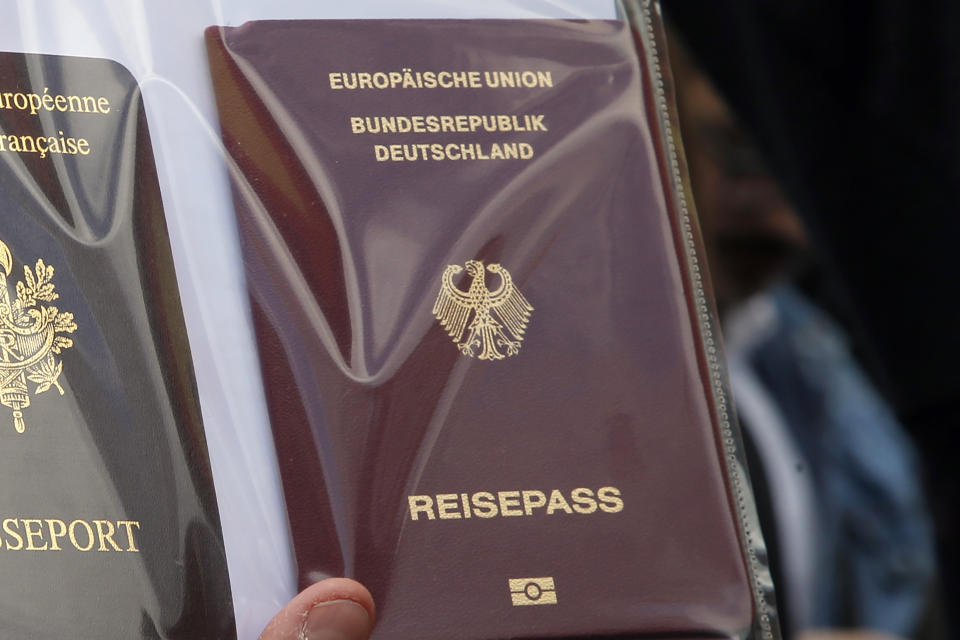 FILE - A person holds German and French, left, passports during a demonstration march to protest government plans to reform the education system, in Paris, France, Tuesday, May 19, 2015. German lawmakers have approved legislation easing rules to gain citizenship and ending restrictions on holding dual citizenship. (AP Photo/Francois Mori, File)