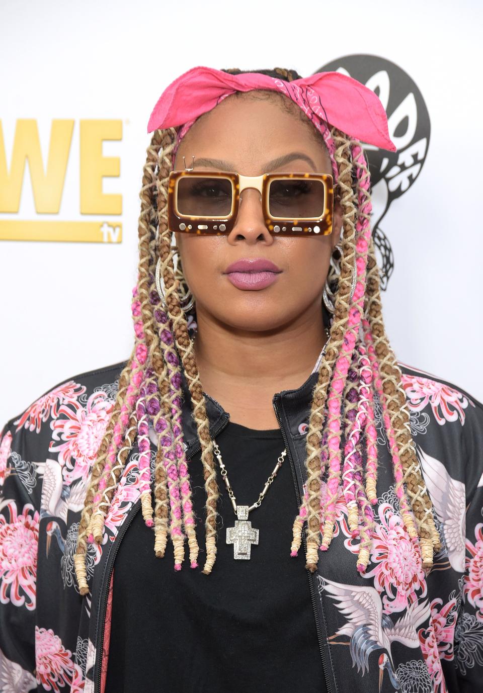 Da Brat poses in a floral jacket with beaded braids and sunglasses