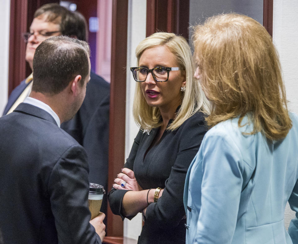 File - In this March 6, 2018, file photo Florida Sen. Lauren Book (D-Plantation), center, speaks with Rep. Jared Even Moskowitz (D-Coral Springs), left, and Rep. Kristin Diane Jacobs (D-Coconut Creek) on the House floor in Tallahassee, Fla. The Florida legislative session was thrown into a chaotic final two weeks as lawmakers scrambled to pass a school safety bill in response to a shooting that killed 17 people at a Parkland high school. Book, whose constituents were affected by the shooting, said that's only partly to blame for the demise of sexual harassment legislation. She also cited "political games" and an "old boy" culture at the Capitol. (AP Photo/Mark Wallheiser, File)