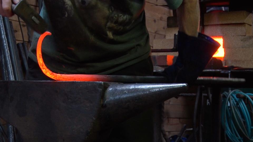 Blacksmith Michael Harrigan hammers a rod into the shape of a hook