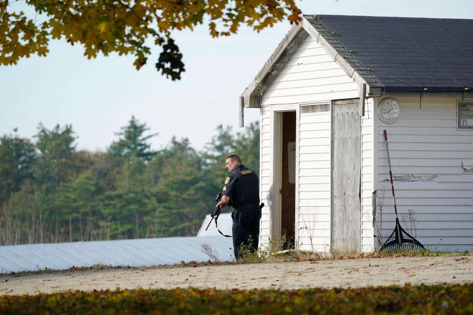 A police officer keeps watch during a manhunt at a farm for the suspect in this week's deadly mass shootings, Friday, Oct. 27, 2023, in Lisbon, Maine. Police are still searching for the man who killed at least 18 in separate shootings at a bowling alley and restaurant in Lewiston on Wednesday. (AP Photo/Robert F. Bukaty)