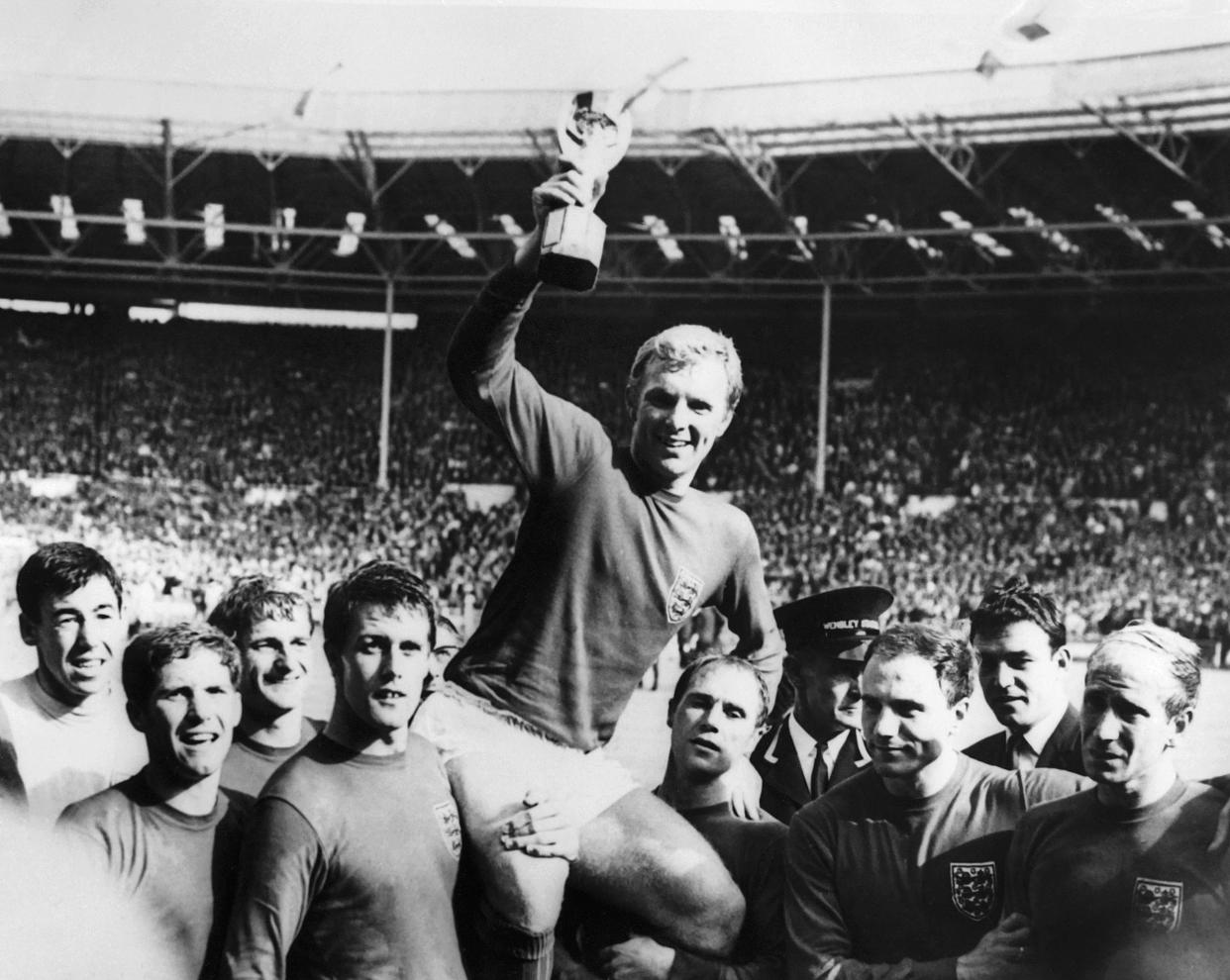 England's national soccer team captain Bobby Moore holds aloft the Jules Rimet trophy as he is carried by his teammates following England's victory over Germany (4-2 in extra time) in the World Cup final 30 July 1966 at Wembley stadium in London.(From L : Gordon Banks, Alan Ball, Roger Hunt, Geoff Hurst - who scored three goals - , Ray Wilson, George Cohen and Bobby Charlton) (Photo by - / CENTRAL PRESS / AFP) (Photo by -/CENTRAL PRESS/AFP via Getty Images)