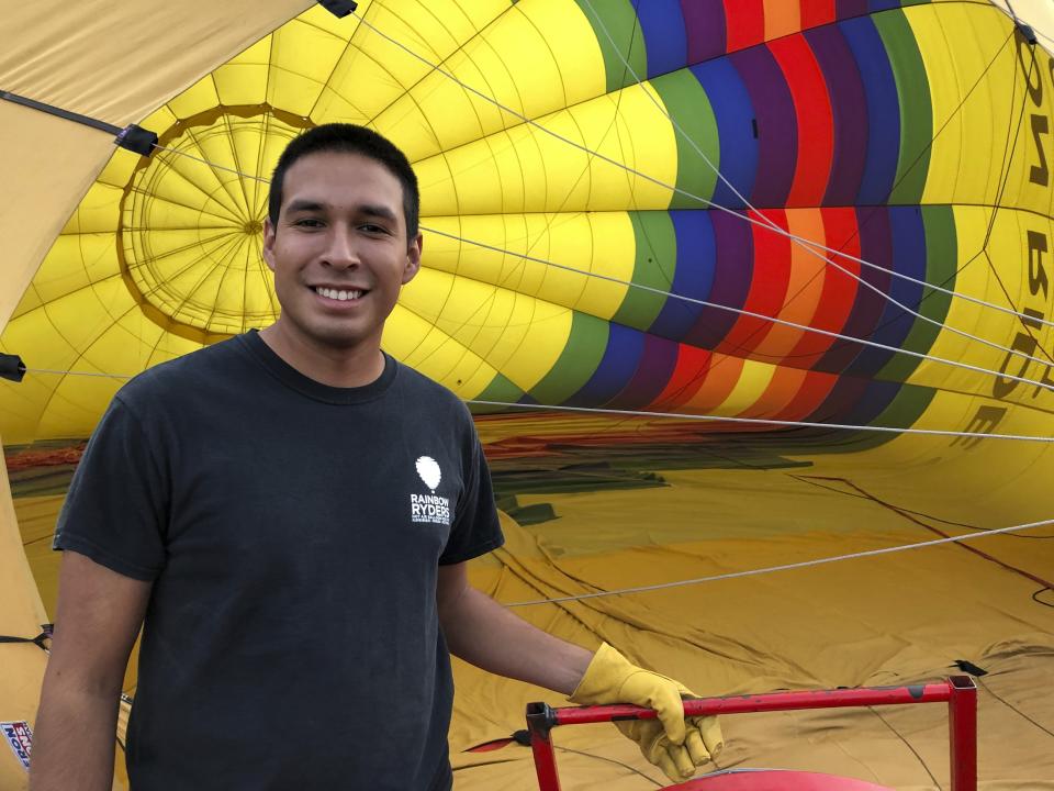 Elijah Sanchez poses for a photo while inflating a hot air balloon in Albuquerque, N.M., on Tuesday, Oct. 1, 2019. Sanchez, 20, will be among the youngest pilots to launch as part of this year's Albuquerque International Balloon Fiesta. The nine-day event is expected to draw several hundred thousand spectators and hundreds of balloonists from around the world. It will kick off Oct. 5 with a mass ascension. (AP Photo/Susan Montoya Bryan)