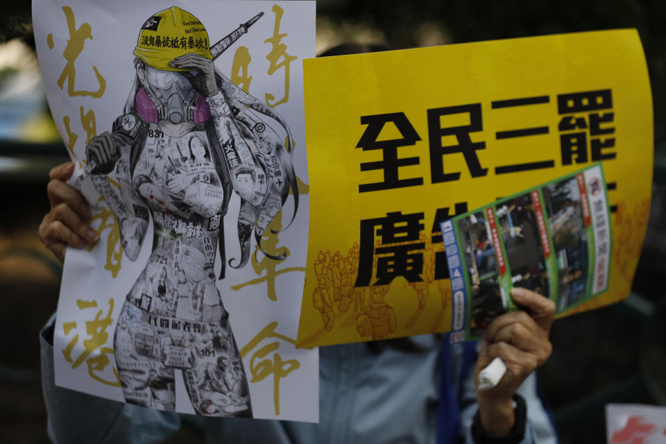 An anti-government supporter holds up banners during a rally by the advertising industry in Hong Kong on Monday, Dec. 2, 2019. Several hundred people who work in advertising in Hong Kong say they will strike this week to support the anti-government protests in the semi-autonomous Chinese territory. The banner, right, read "Advertising Industry joins all citizens three boycotts." (AP Photo/Vincent Thian)