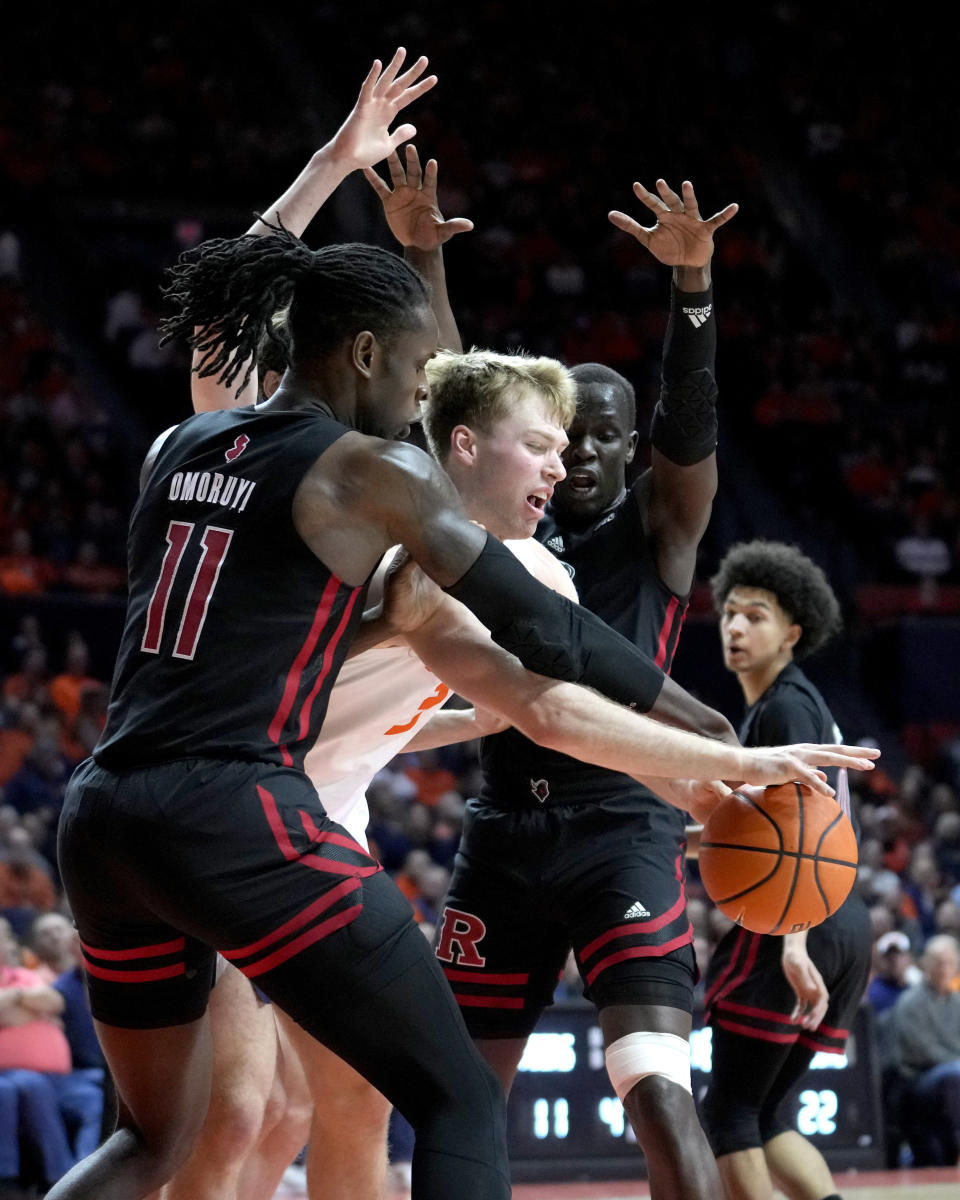 Illinois' Marcus Domask is pressured by Rutgers' Clifford Omoruyi (11) and Mawot Mag during the first half of an NCAA college basketball game Sunday, Jan. 21, 2024, in Champaign, Ill. (AP Photo/Charles Rex Arbogast)