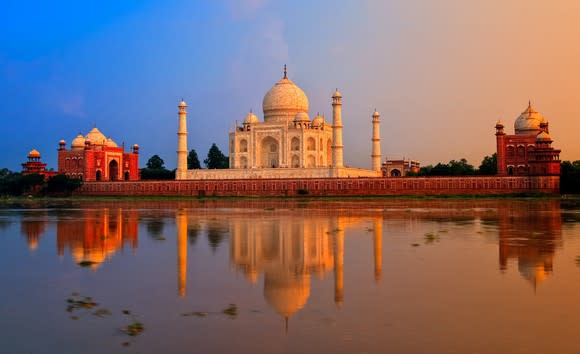 Taj Mahal with two other buildings and the Yamuna River in the foreground.