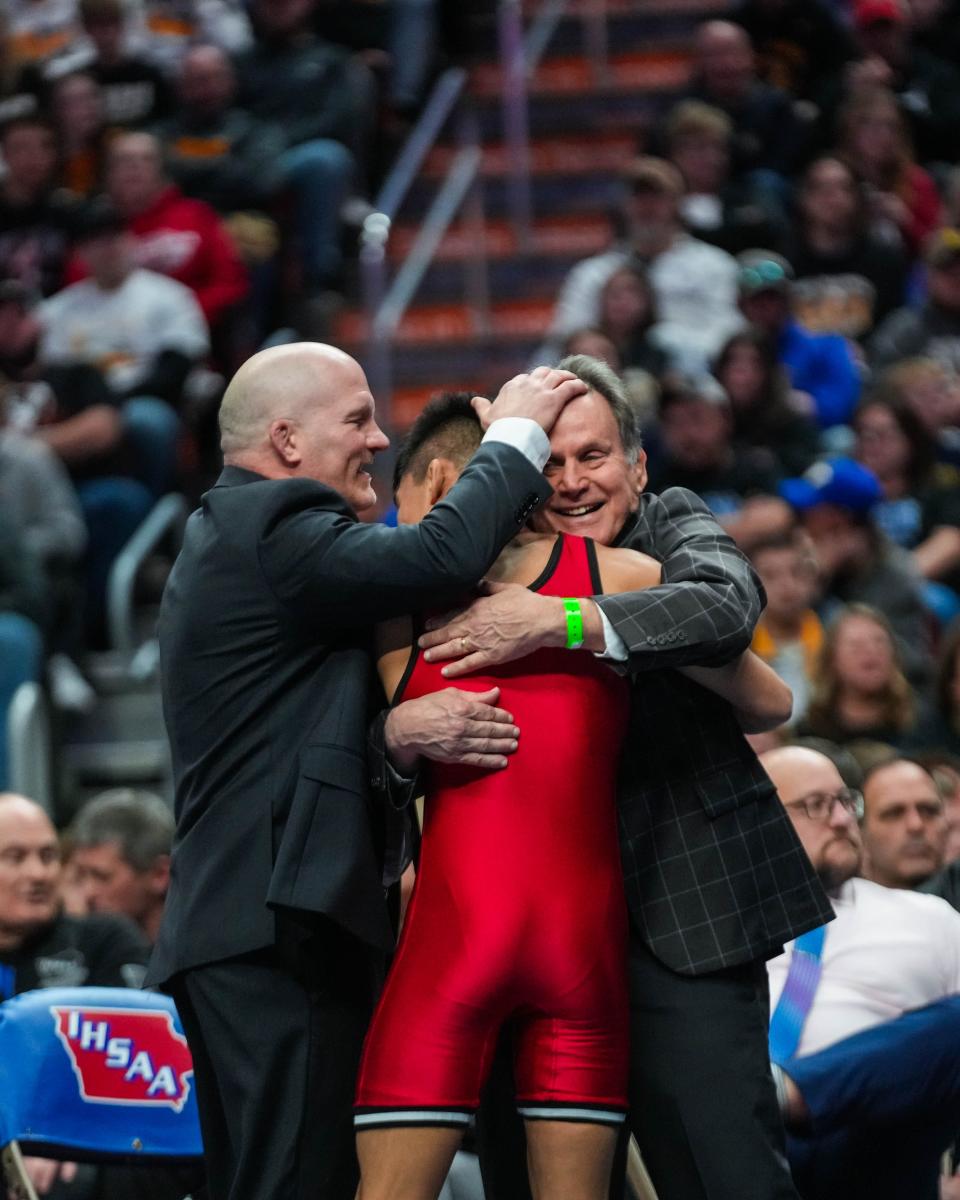 Lisbon's Brandon Paez gets a hug from coaches after defeating West Hancock's Teague Smith at 120 pounds during Saturday's championship round of the Class 1A state wrestling tournament.