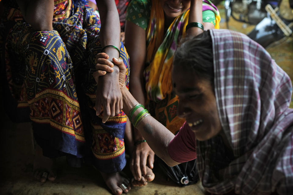 A woman holds the hand of her relative as family members of people trapped under rubble wail after a landslide washed away houses in Raigad district, western Maharashtra state, India, Thursday, July 20, 2023. While some people are reported dead many others feared trapped under piles of debris. (AP Photo/Rafiq Maqbool)