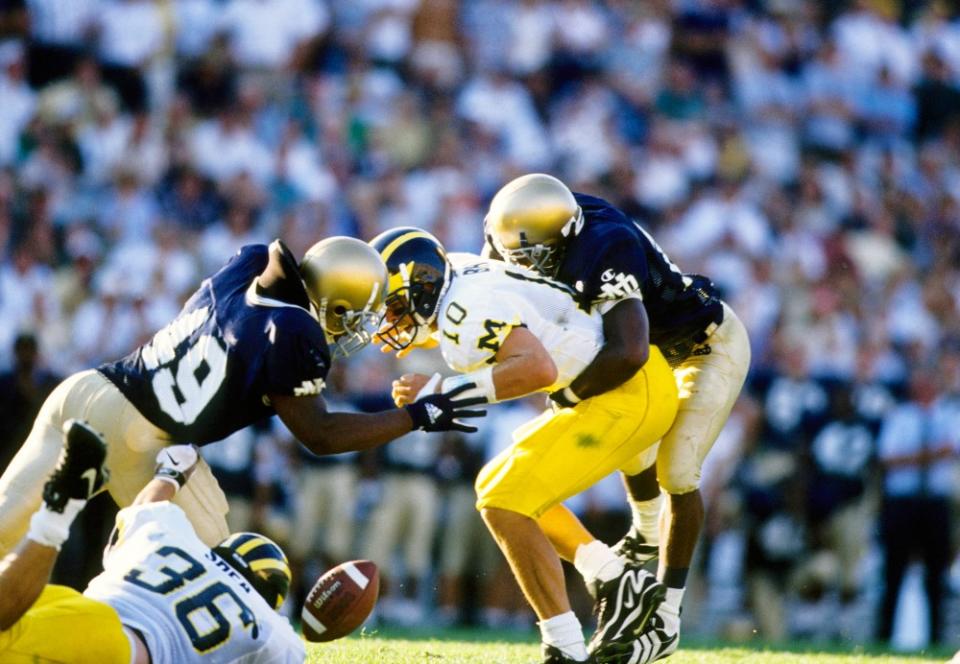 Sep 5, 1998; Notre Dame, IN, USA; FILE PHOTO; Michigan Wolverines quarterback Tom Brady (10) striped sacked by Notre Dame Fighting Irish defensive end Deveron Harper (10) and Joe Thomas (49) at the Notre Dame Stadium. Mandatory Credit: RVR Photos-USA TODAY Sports