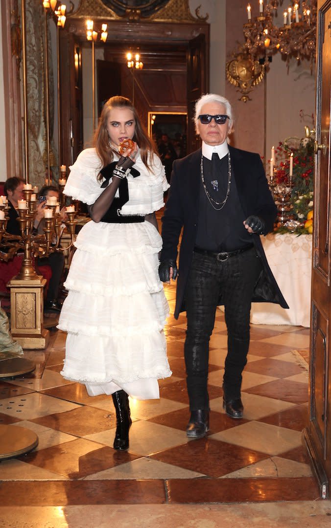 <p>The designer walks the runway with model Cara Delevigne following the Chanel Metiers d’Art Collection 2014/15 show in 2014. <em>[Photo: Getty]</em> </p>