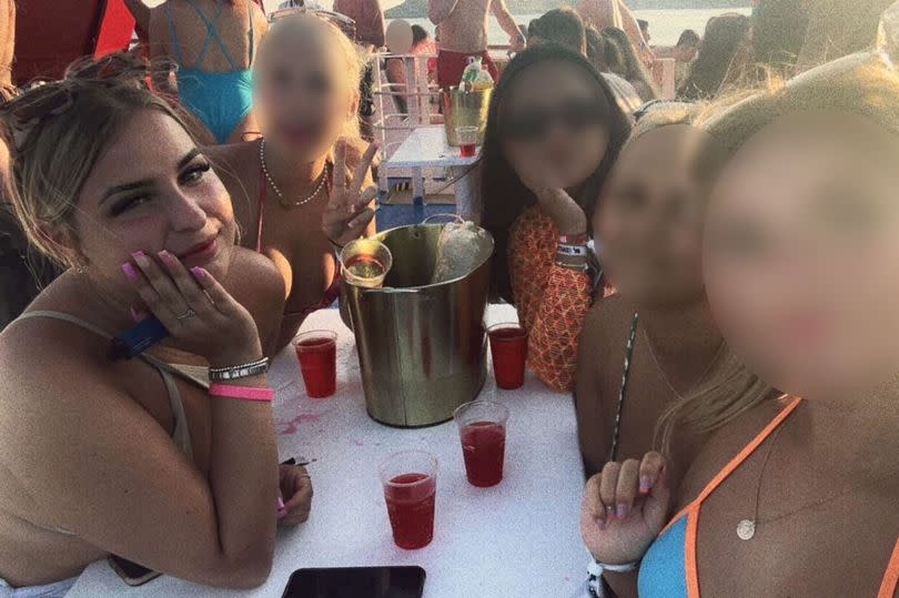 A woman sat round a table with drinks in Zante with her friends who have their faces blurred in the photo