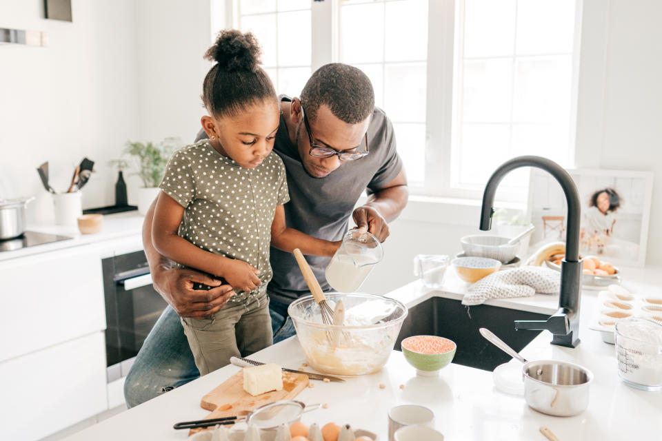 Dad and daughter in the kitchen baking together making cupcakes