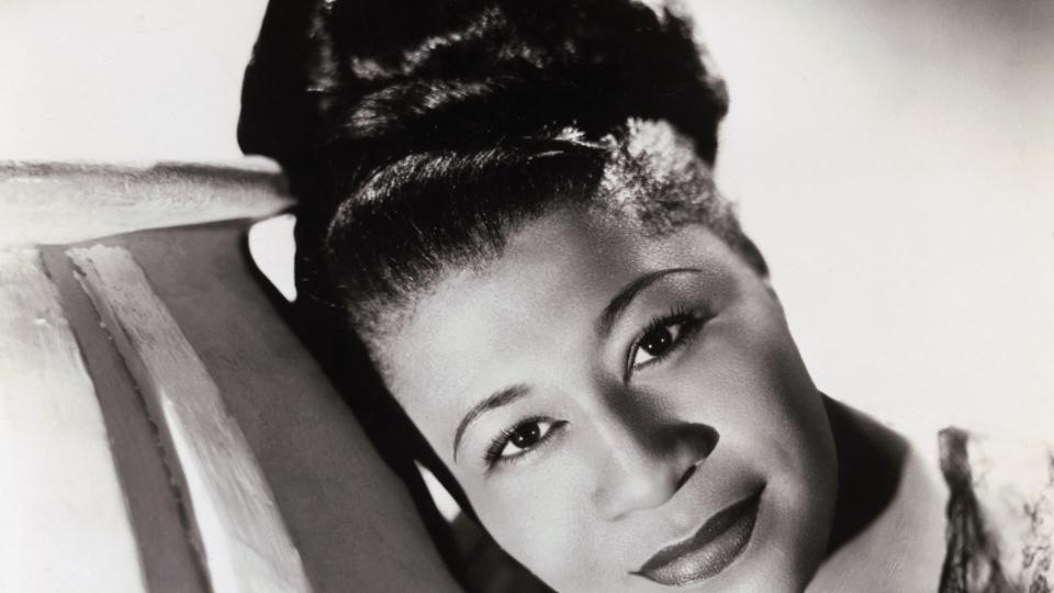 ella fitzgerald with her hair in a bun and leaning against a prop