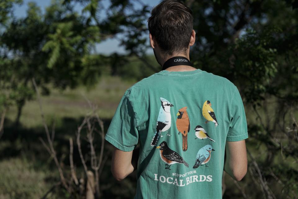 Brady Karg, an education coordinator at Spring Creek Prairie Audubon Center, wears a birding T-shirt while on a birdwatching tour, Tuesday, June 20, 2023, in Denton, Neb. North America's grassland birds are deeply in trouble 50 years after adoption of the Endangered Species Act, with numbers plunging as habitat loss, land degradation and climate change threaten what remains of a once-vast ecosystem. (AP Photo/Joshua A. Bickel)