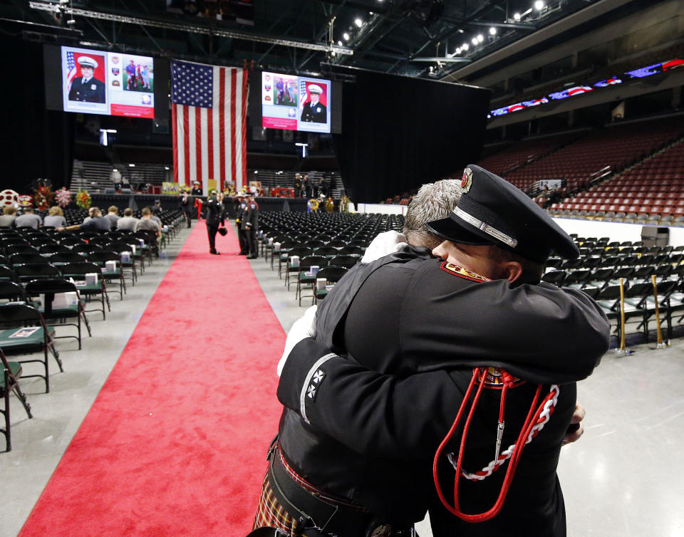 Firefighters Chris Thurman, left, and Jefferson Halladay of Unified Fire Authority hug before the funeral of Draper Battalion Chief Matt Burchett in at the Maverik Center in West Valley City, Utah, on Monday, Aug. 20, 2018. Battalion Chief Matt Burchett was hit by a tree Monday while fighting a wildfire north of San Francisco. He was flown to a hospital where he succumbed to his injuries. (Ravell Call/The Deseret News via AP)