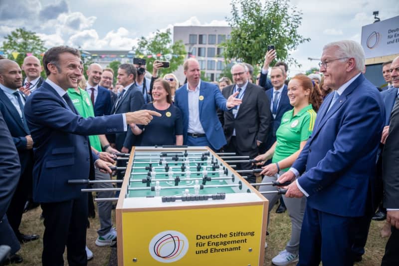 French President Emmanuel Macron visits the democracy festival to mark 75 years of the Basic Law together with German President Frank-Walter Steinmeier and they stand at a table football table. Michael Kappeler/dpa