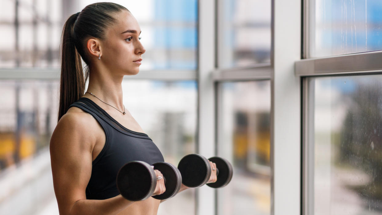  A woman doing a bicep curl with a pair of dumbbells. 