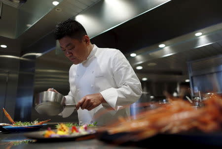 Yoshihiro Narisawa, the owner and chef of Tokyo's French restaurant Narisawa, prepares a dish called "Five flavors", for an early spring menu which includes Akaza Ebi, or langoustine shrimp, from Suruga Bay in central Japan, accented with "green caviar" of various green peas, along with the petals of rucola flowers and viola, at the kitchen of Narisawa in Tokyo March 26, 2015. REUTERS/Yuya Shino