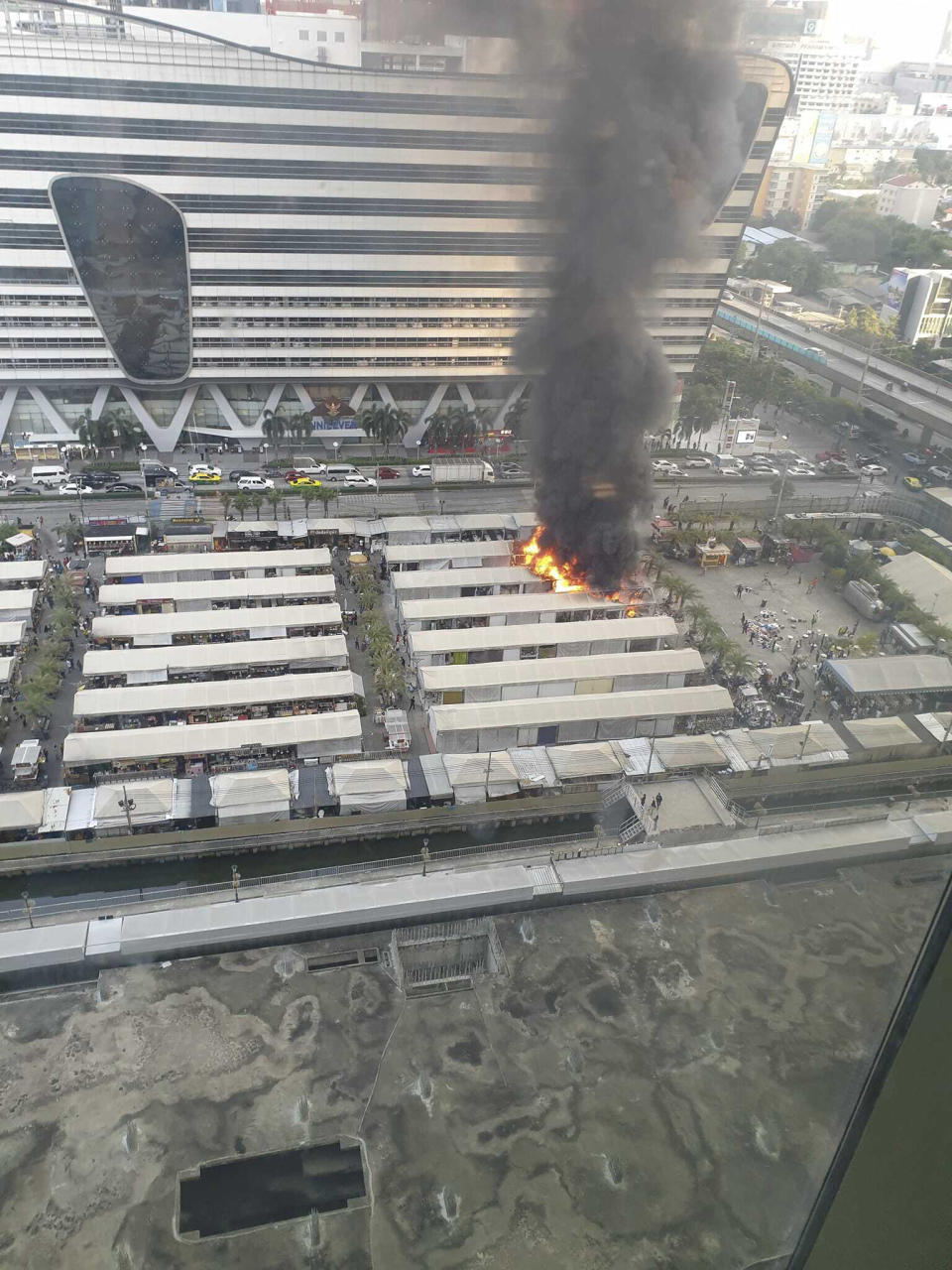 This photo provided by Dusadee Deena Chiewcharnvalichakij shows a fire at a popular open market, as seen from a nearby building in central Bangkok on Wednesday, Dec. 13, 2023, spewing clouds of black smoke visible from all over the Thai capital. It caused minimal damage and only one known injury, a fire official said. (Dusadee Deena Chiewcharnvalichakij via AP)