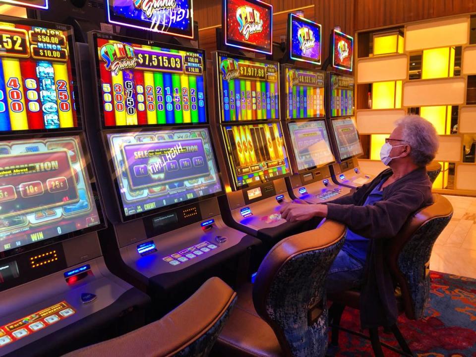 A patron wearing a mask, plays a slot machine at the Seminole Hard Rock Hotel & Casino, Friday, March 20, 2020, near Hollywood, Fla.