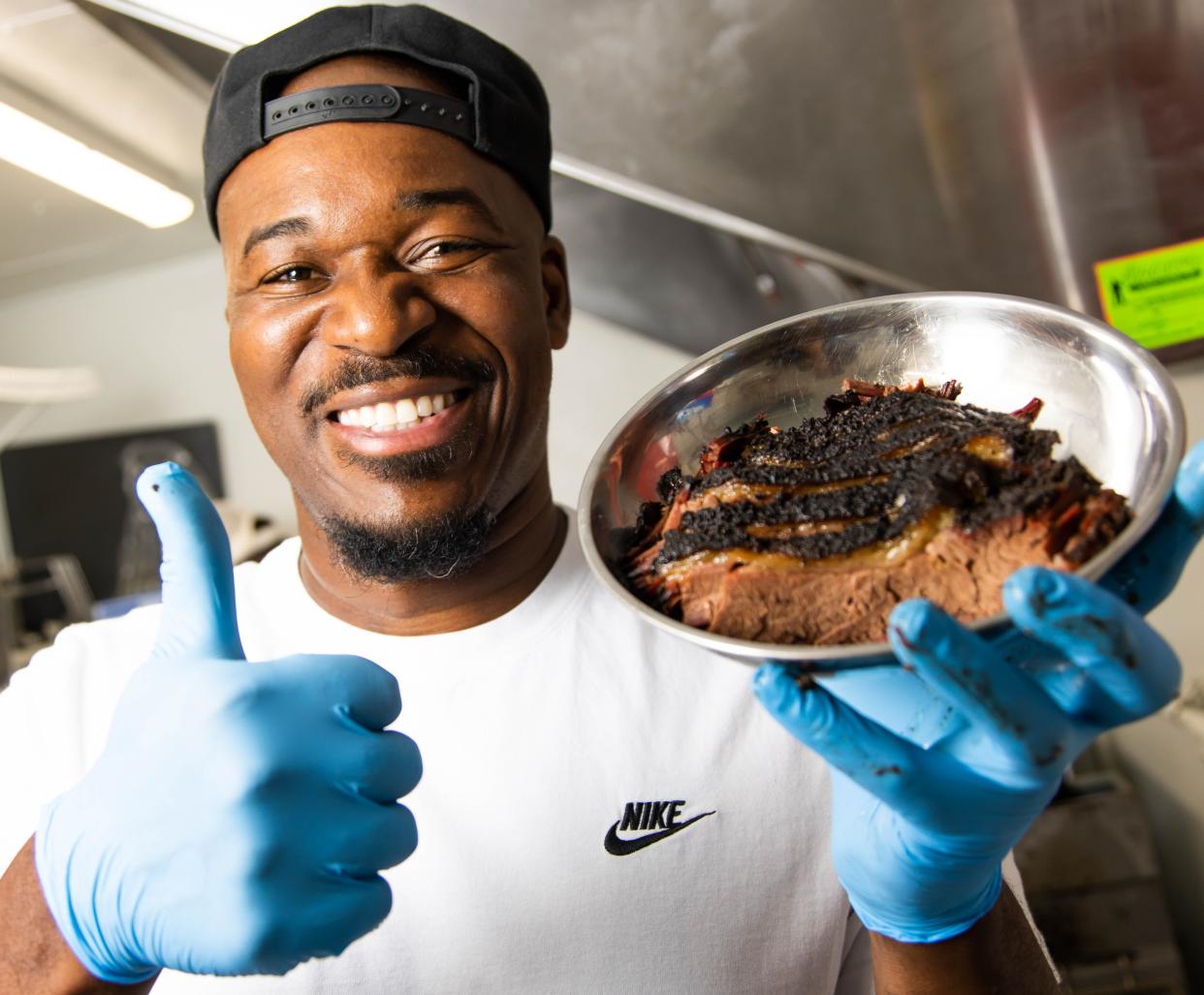 Rashad Jones, owner of Big Lee's - Serious About Barbecue, gives a thumbs up while serving his brisket Tuesday morning. Jones won this season of "BBQ Brawl" on the Food Network. In the final episode, which aired Monday night. Jones beat out two other contestants. He won by cooking a whole suckling pig along with making four sides and a dessert.