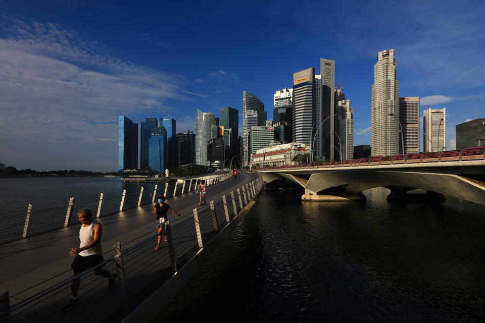 SINGAPORE - JUNE 07:  People jog along the Jubilee Bridge with the central business district seen in the background on June 7, 2020 in Singapore. From June 2, Singapore embarked on phase one of a three phase approach against the coronavirus (COVID-19) pandemic as it began to ease the partial lockdown measures by allowing the safe re-opening of economic activities which do not pose high risk of transmission. This include the resumption of selected health services, re-opening of schools with school children attending schools on rotational basis, manufacturing and production facilities, construction sites that adhere to safety measures, finance and information services that do not require interactions and places of worship, amongst others. Retail outlets, social and entertainment activities will remain closed and dining in at food and beverage outlets will still be disallowed. The government will further ease restriction by the middle of June if the infection rate within the community remains low over the next two weeks.  (Photo by Suhaimi Abdullah/Getty Images)