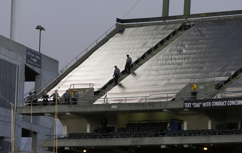 FILE - Law enforcement officials walk in the upper deck of Oakland Coliseum after an NFL football game between the Oakland Raiders and the Tennessee Titans in Oakland, Calif., Nov. 24, 2013. The new Oakland Ballers independent baseball team is hoping to incorporate a bit of Oakland sports history in its renovated ballpark as the club prepares for the opener next month. An expansion team in the independent Pioneer League, the "B's" are inquiring about purchasing some or all of the approximately 5,000 unused bleacher seats that formerly were brought in for Oakland Raiders games. (AP Photo/Jeff Chiu, File)