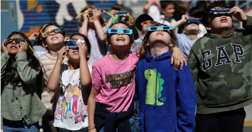 美國孩童紛紛戴上日食眼鏡，搶看這波難得的天文奇景。（圖／達志／路透社）