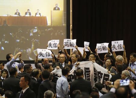 Pro-democracy lawmakers hold up a banner and signs during a protest as Li Fei (seen on screen), deputy general secretary of the National People's Congress (NPC) standing committee, speaks during a briefing session in Hong Kong September 1, 2014. REUTERS/Bobby Yip