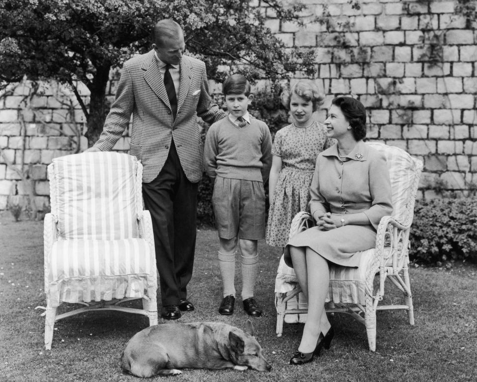 Queen Elizabeth II and Prince Philip, Duke of Edinburgh with their children, Prince Charles and Princess Anne, below the East Terrace on the South Front of Windsor Castle, Berkshire, June 1959. Sugar, the Queen's corgi, takes a nap at her feet. (Photo by Fox Photos/Hulton Archive/Getty Images)