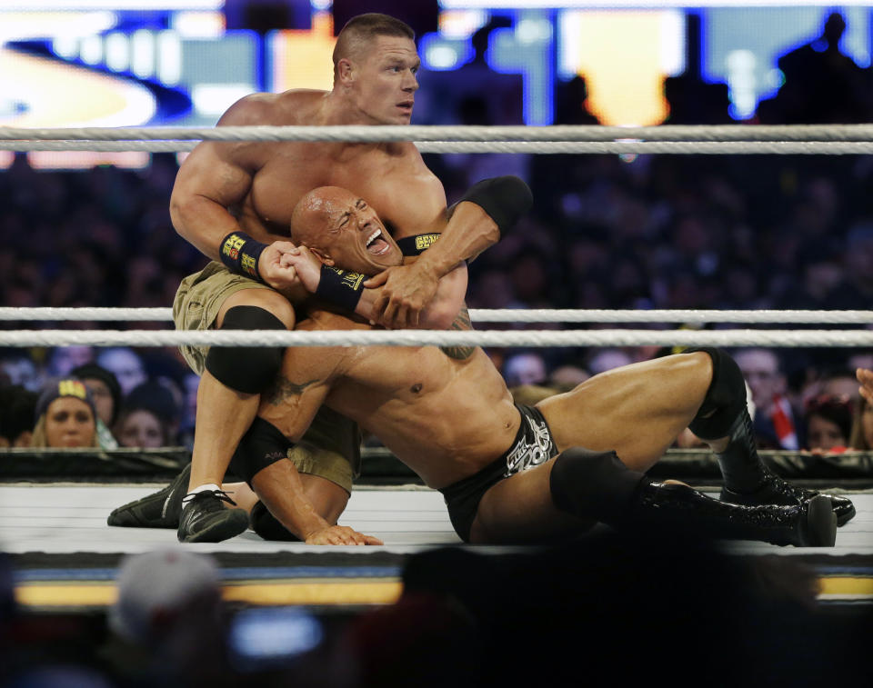 FILE - Wrestler John Cena, top, chokes Dwayne Douglas Johnson, known as The Rock, as they wrestle, April 7, 2013, in East Rutherford, N.J., during Wrestlemania. Cena announced Saturday, July 6, 2024, that he will retire from professional wresting next year after two decades in the ring. (AP Photo/Mel Evans, File)