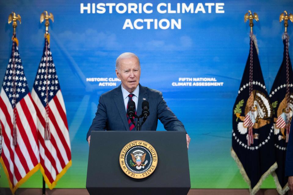 President Joe Biden delivers remarks beneath signage that reads: Historic Climate Action.