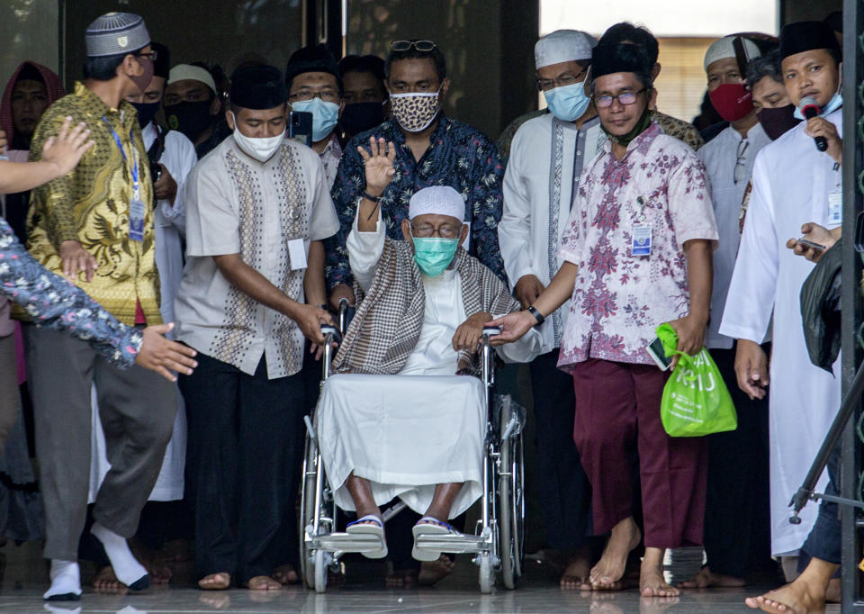 Islamic cleric Abu Bakar Bashir, center, waves from a wheelchair upon arrival at the Al Mukmin Islamic Boarding School where he resides in Solo, Central Java, Indonesia, Friday, Jan. 8, 2021. The firebrand cleric who inspired the Bali bombers and other violent extremists walked free from prison Friday after completing his sentence for funding the training of Islamic militants. (AP Photo)