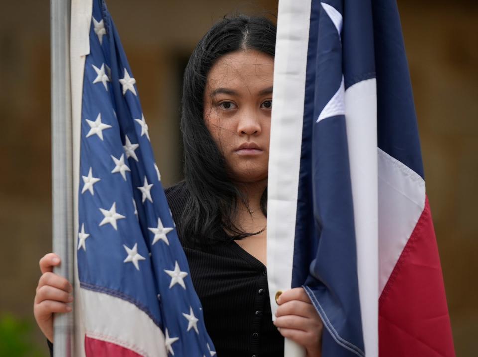 Akeela Kongdara with Asian Texans for Justice holds U.S. and Texas flags at a Tuesday's news conference at Austin City Hall.