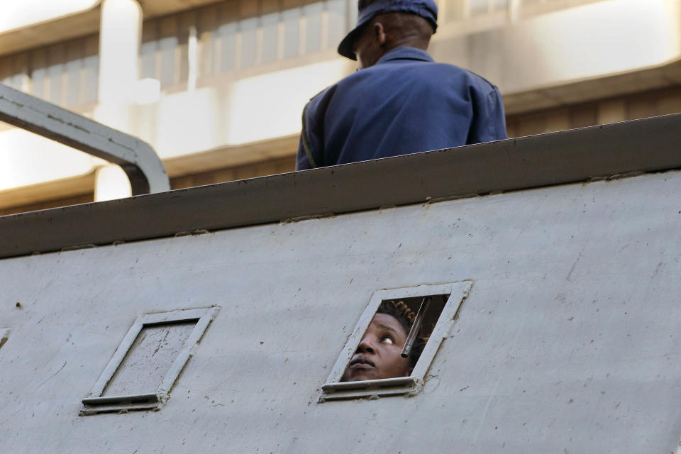 FILE - In this Thursday Aug. 2, 2018 file photo a supporter of Zimbabwean's main opposition party MDC, who was arrested following clashes, is seen detained in a police vehicle outside the MDC headquarters, in Harare. Gunfire, tear gas, and burning cars disrupted Harare's streets Wednesday as armed riot police and army troops clashed with rock-throwing opposition supporters after the Electoral Commission announced it would not give the results in July 30 2018 presidential elections today.(AP Photo/Jerome Delay, File)